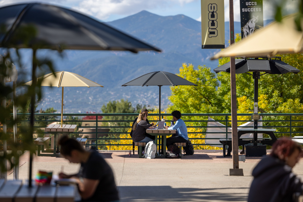 students sitting together in on the University Center plaza with Pikes Peak in the background